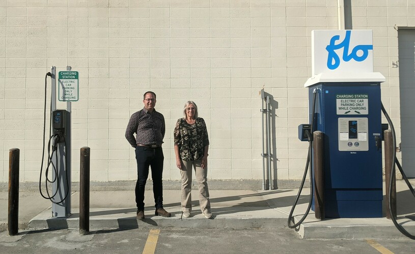 Picture of two people standing beside an electric car charger